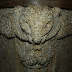 The corner of a square, Norman font carved with a stylised animals head looking directly at the camera