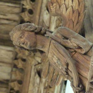 A carved angel holding a shield supporting the roof of the church