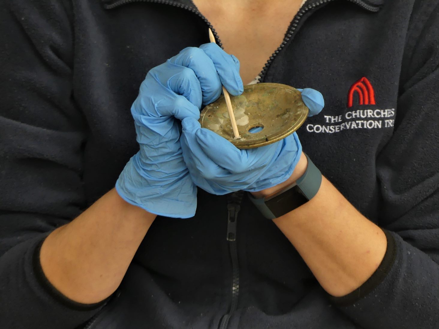 Close up image of a person cleaning a brass item