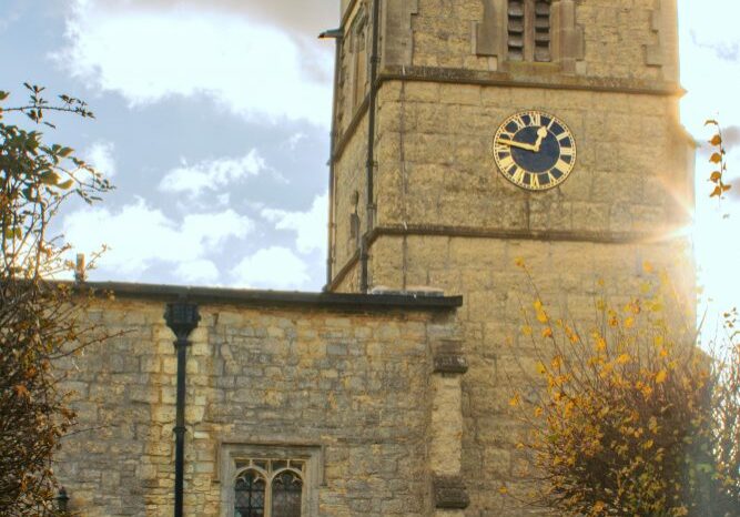 St John the Baptist church, Granborough, exterior Church bell tower with clock and sunbeams