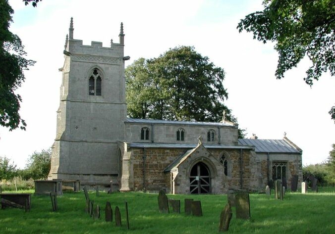 St Mary's, Garthorpe exterior from south Church with bell tower surrounded by sun dappled churchyard