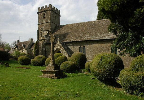 St Mary, Edgeworth, Glos. exterior- ChrichBrown Medieval church with stone cross in churchyard
