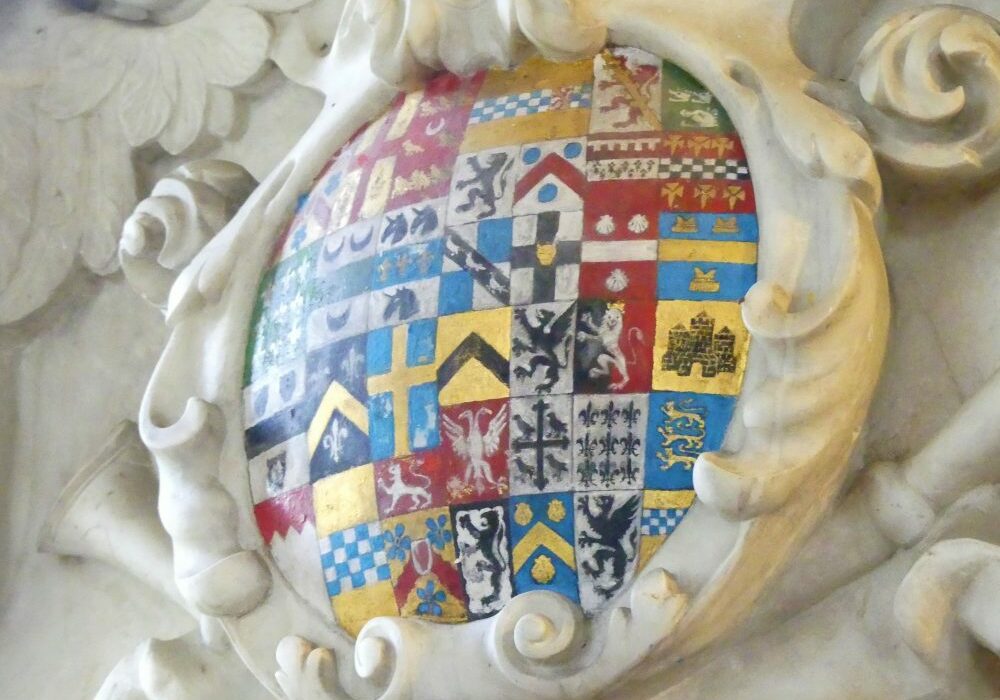 ChurchImages Norfolk Cranworth Monument 1 A circular marble surround filled with approximately 40 tiny coats of arms, in red, blue, gold, black and white, showing animals, birds, crosses, chevrons and squares