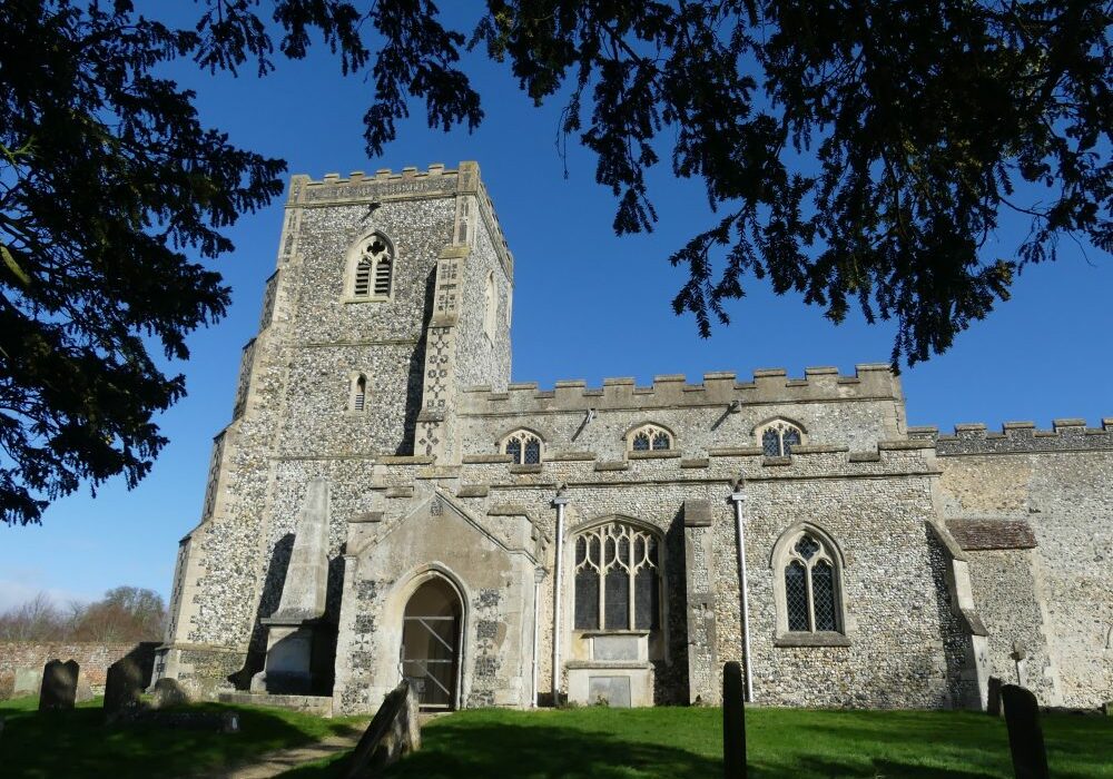 ChurchImages Suffolk Dalham Ext A flint church with a low, solid looking tower, the image is framed by yew trees