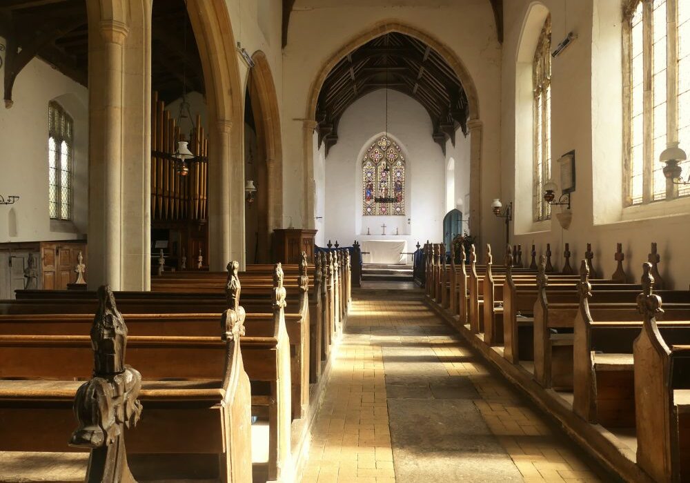 ChurchImages Norfolk Field Dalling Interior View inside a warm sunlight church with a yellow brick and tile floor and carved pews.