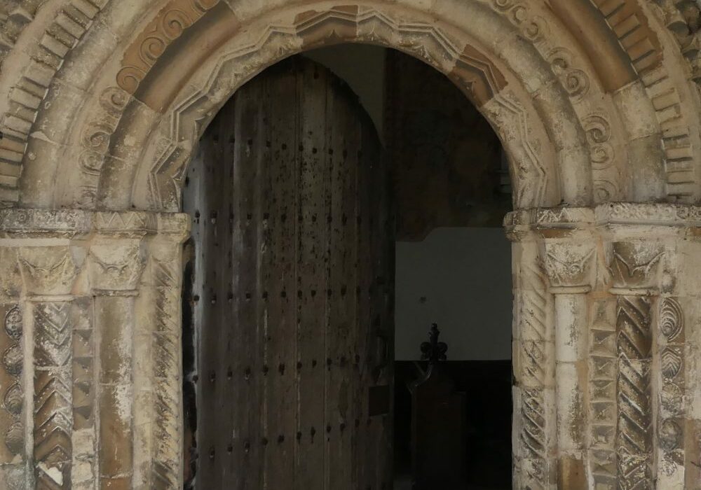 ChurchImages Norfolk Mundham Door A stone doorway with a round arch. the door is surrounded by pillars and concentric arches each carved in regular geometric patterns