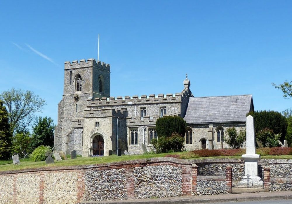 St Swithin Gt Chishill Church exterior, square tower with clock, turreted nave, large porch, flint. Behind flint wall. War memorial