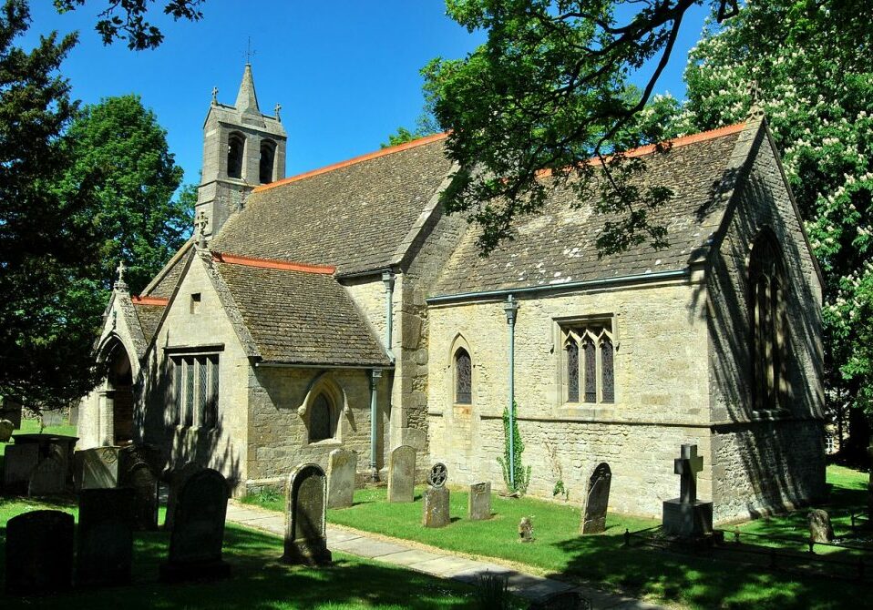 Small stone church in sunlight with deep blue sky surrounded by trees